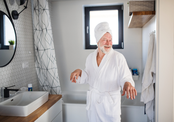 A senior man doing morning routine in bathroom indoors at home.