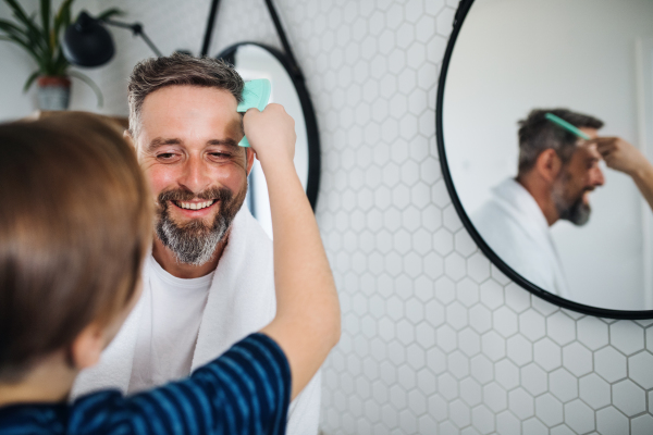 A mature father with small son in the bathroom in the morning.