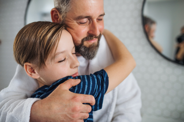 A mature father with small son in the bathroom in the morning, hugging.