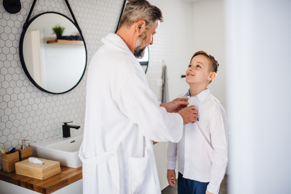 A mature father with small son getting dressed in the bathroom in the morning.