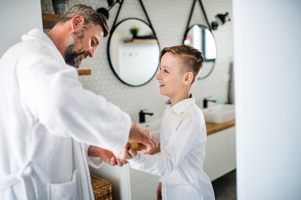 A mature father with small son getting dressed in the bathroom in the morning.