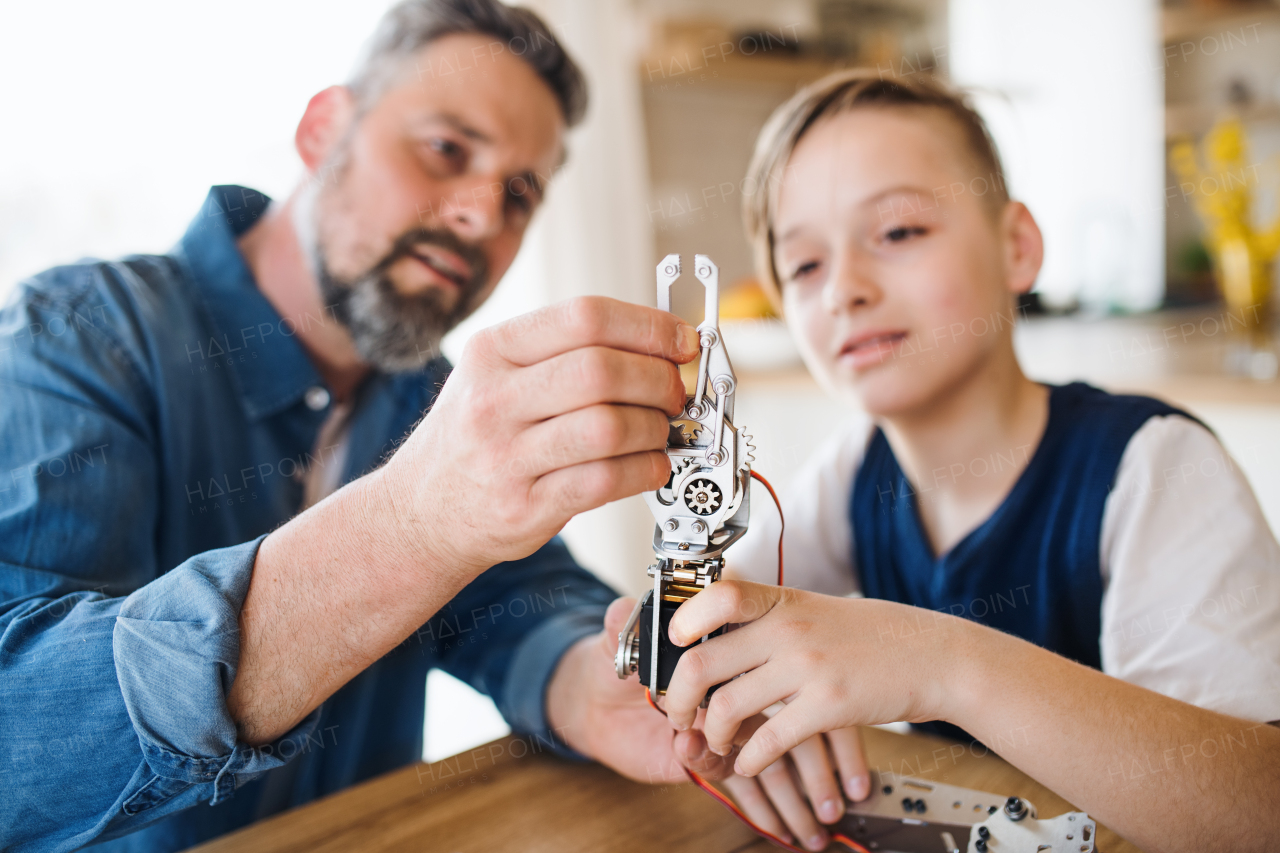 A mature father with small son sitting at table indoors, working on school project.