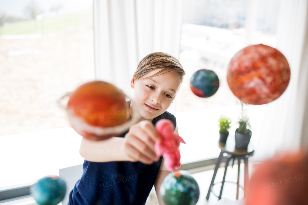 A small boy with model of solar system indoors, playing.