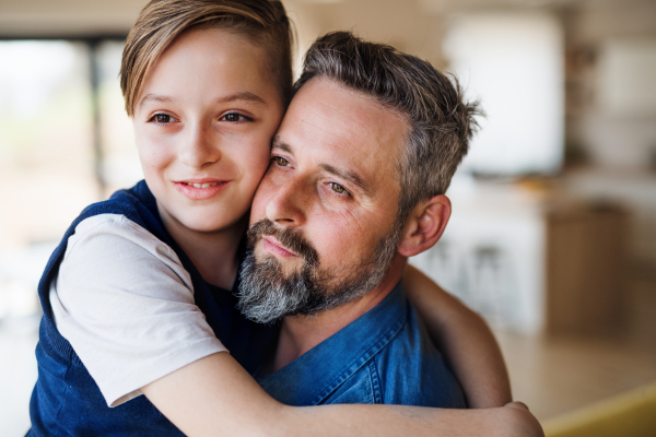 Mature father with small schoolboy son having fun indoors.