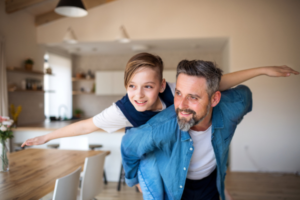 Mature father with small schoolboy son having fun indoors.