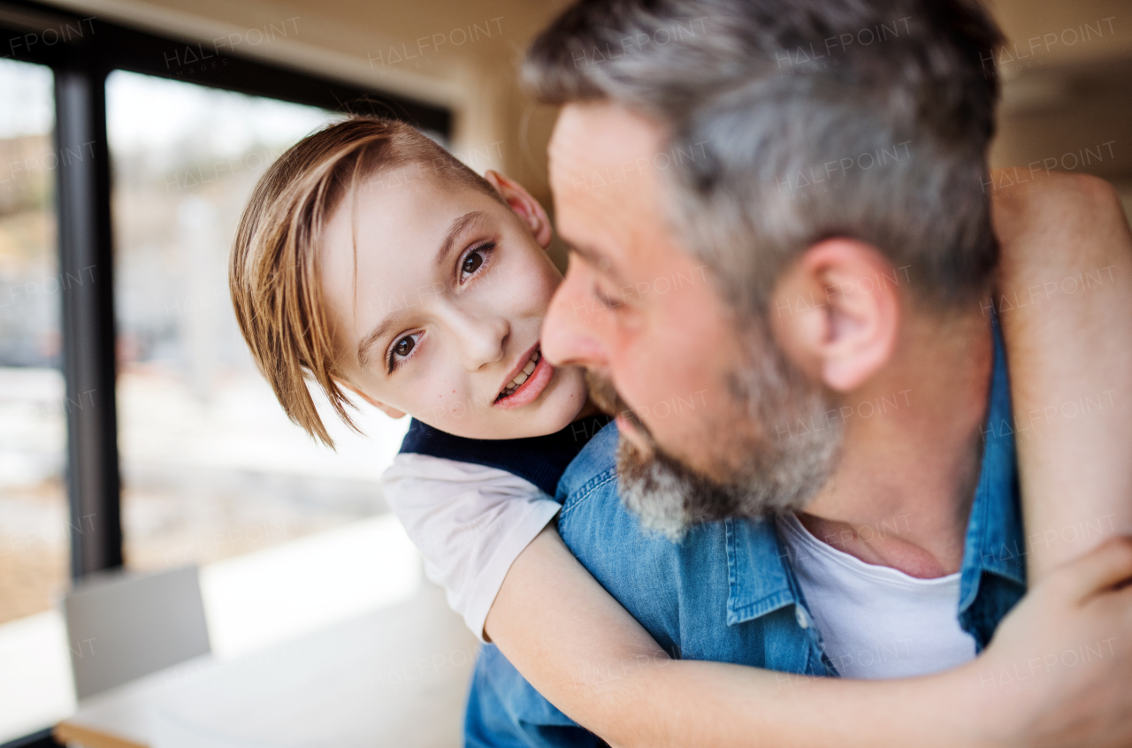 Mature father with small schoolboy son having fun indoors.