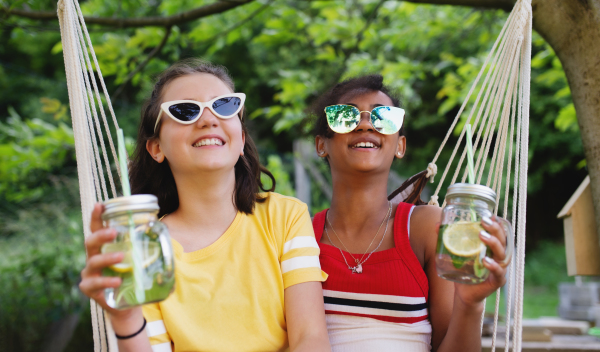 Front view of cheerful young teenager girls friends outdoors in garden, having fun.