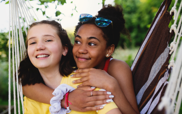 Front view of cheerful young teenager girls friends outdoors in garden, resting.