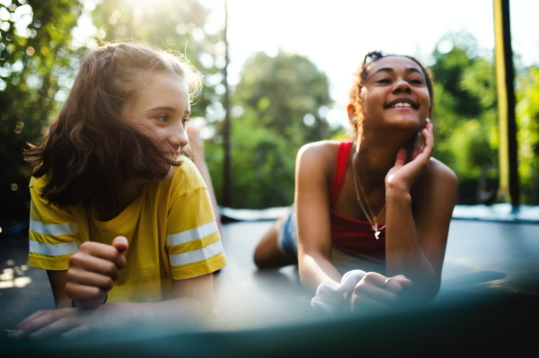 Front view of cheerful young teenager girls friends outdoors in garden, laughing.