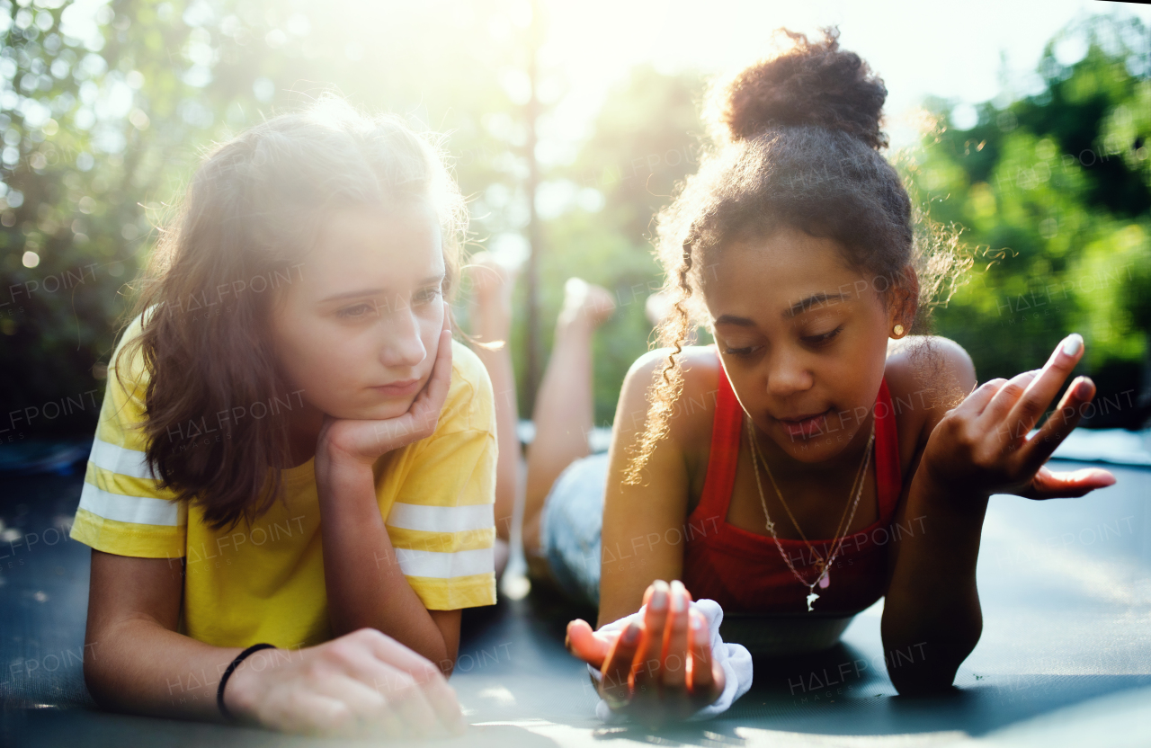 Front view of cheerful young teenager girls friends outdoors in garden, talking.