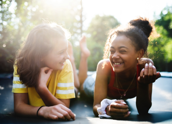 Front view of cheerful young teenager girls friends outdoors in garden, talking and laughing.