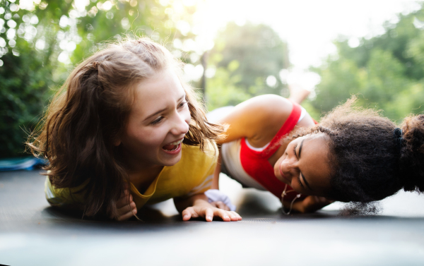 Front view of cheerful young teenager girls friends outdoors in garden, laughing.