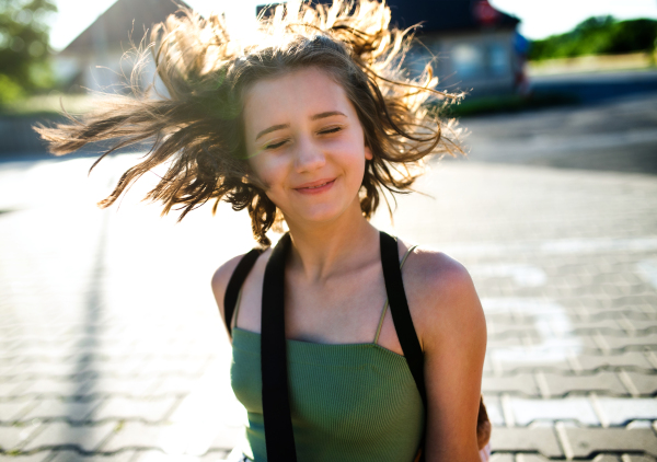 Portrait of teenager girl with eyes closed walking outdoors in city, having fun.