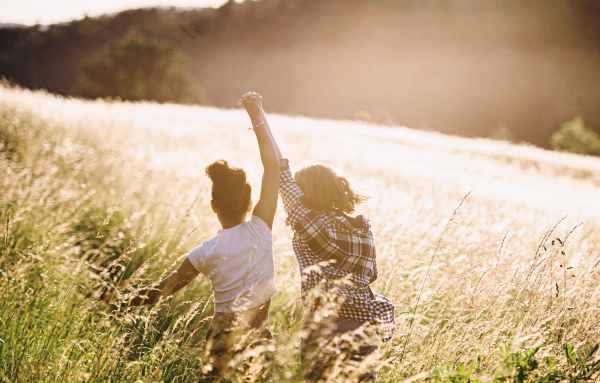 Rear view of cheerful young teenager girls friends outdoors in nature, having fun.