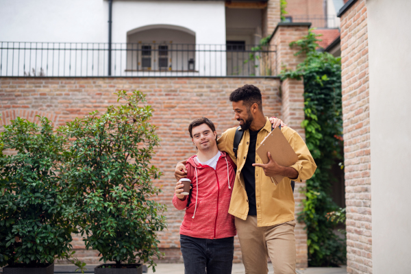 A young man with Down syndrome and his mentoring friend walking and embracing outdoors