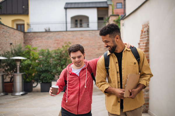 A young man with Down syndrome and his mentoring friend walking and talking outdoors