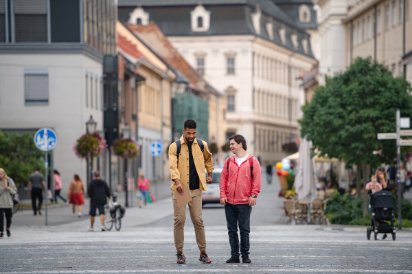 A young man with Down syndrome and his mentoring friend walking and talking outdoors