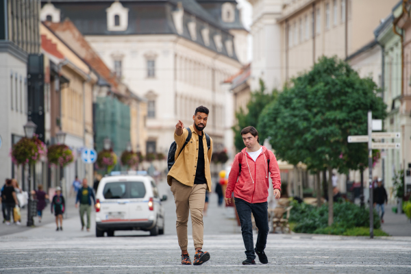 A young man with Down syndrome and his mentoring friend walking and talking outdoors