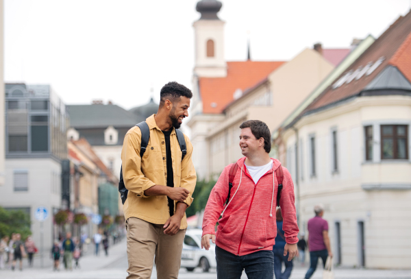 A young man with Down syndrome and his mentoring friend walking and laughing outdoors