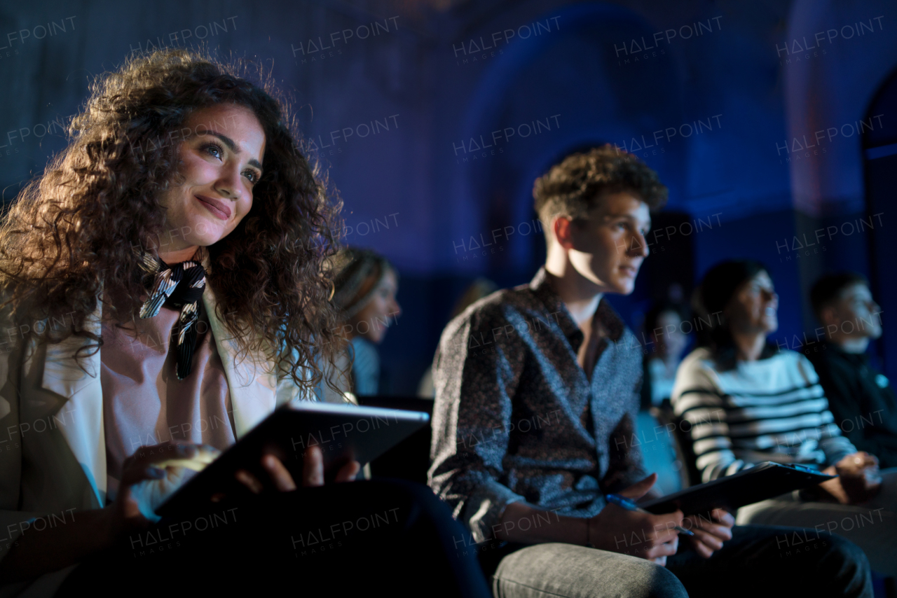 A group of people making notes while listening to presentation at conference.