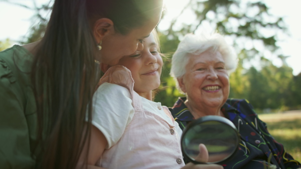 A small girl with mother and grandmother resting in a park, talking.