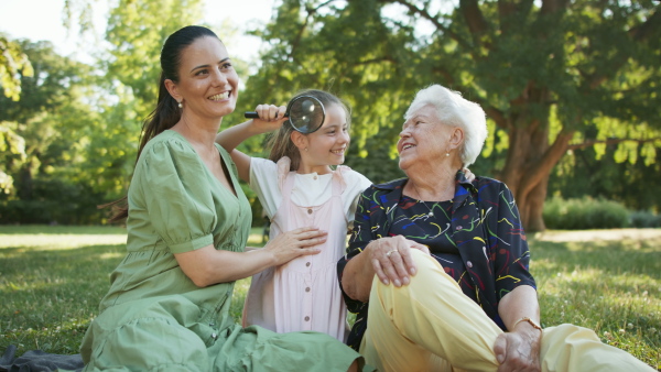 A small girl with mother and grandmother resting in a park, talking.