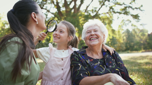 A small girl with mother and grandmother resting in a park, talking.