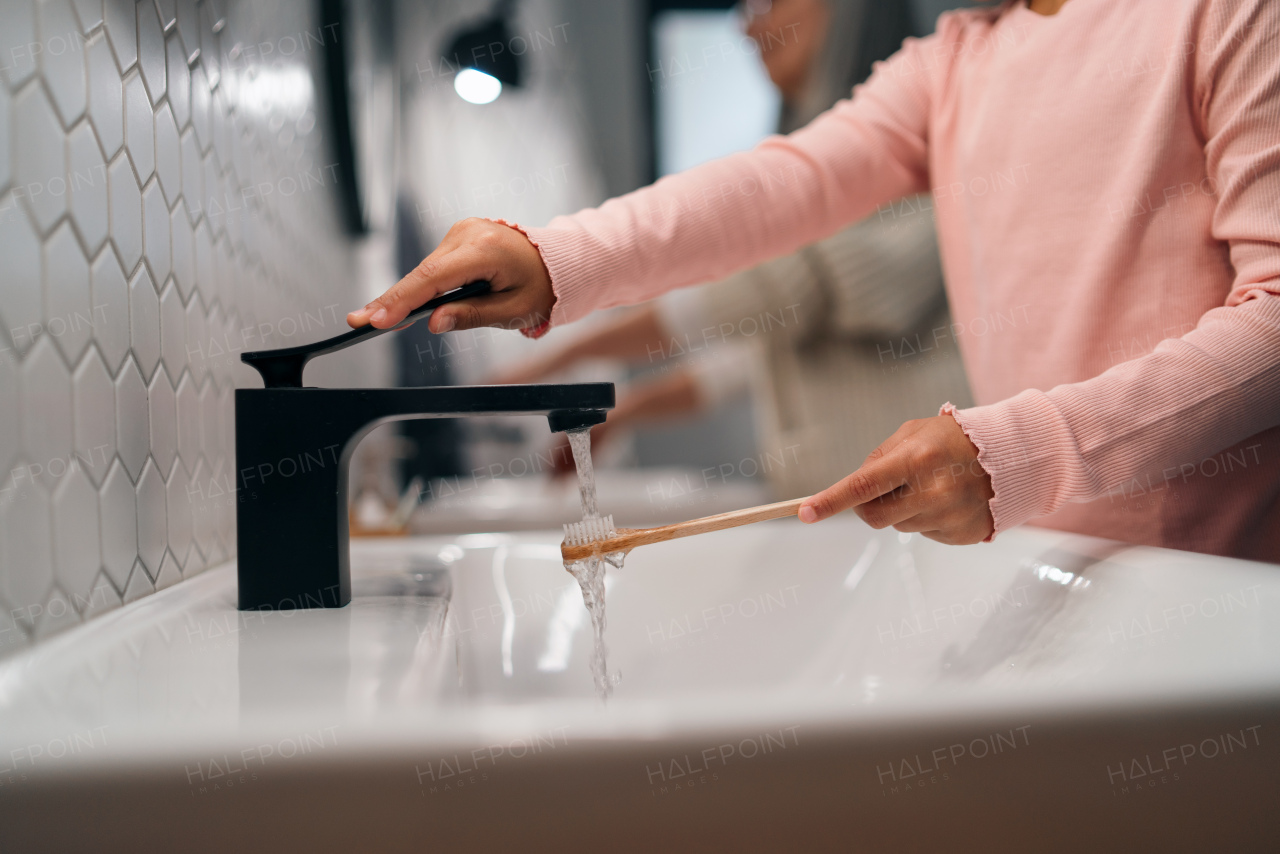 A close-up of little girl with eco toothbrush in bathroom, morning routine concept.