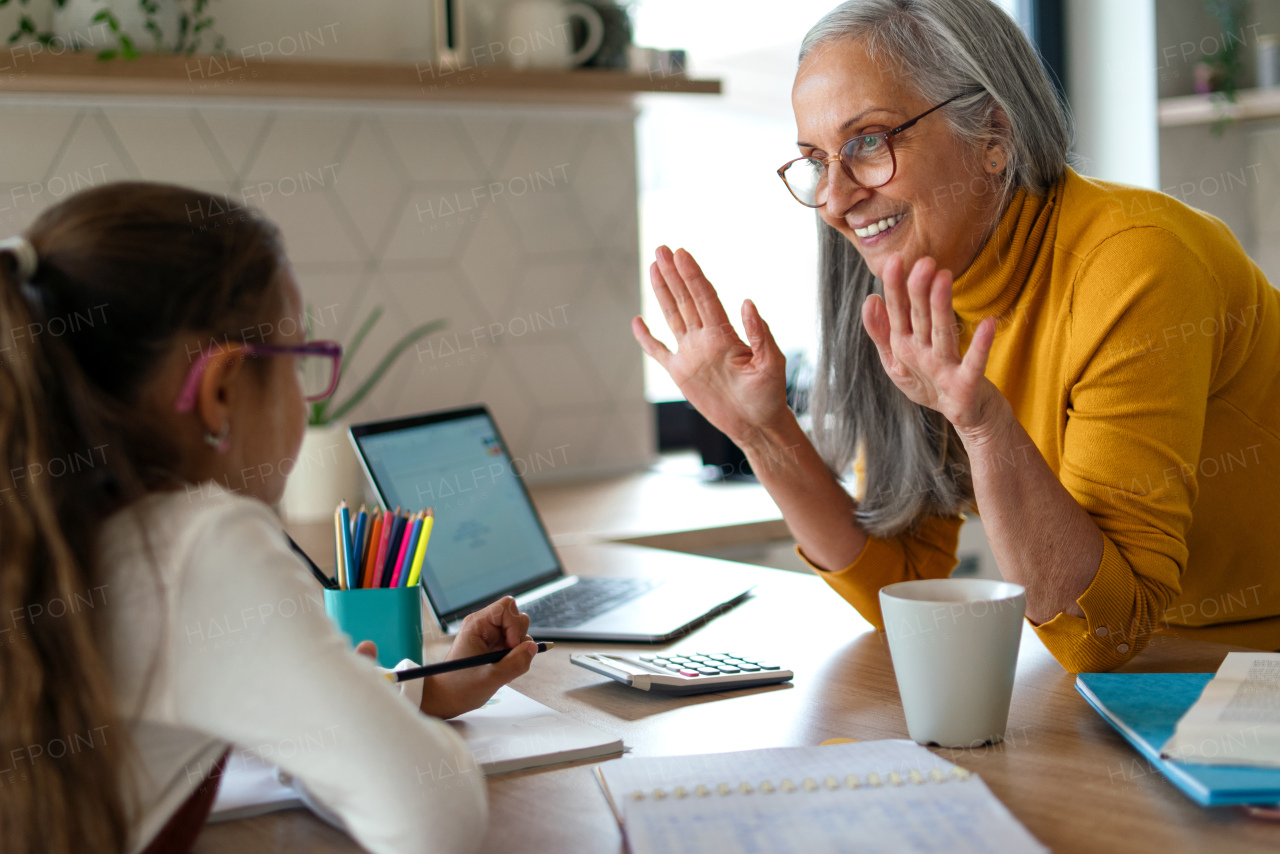 A small girl with senior grandmother doing maths homework at home.