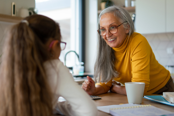 A small girl with senior grandmother doing homework at home.