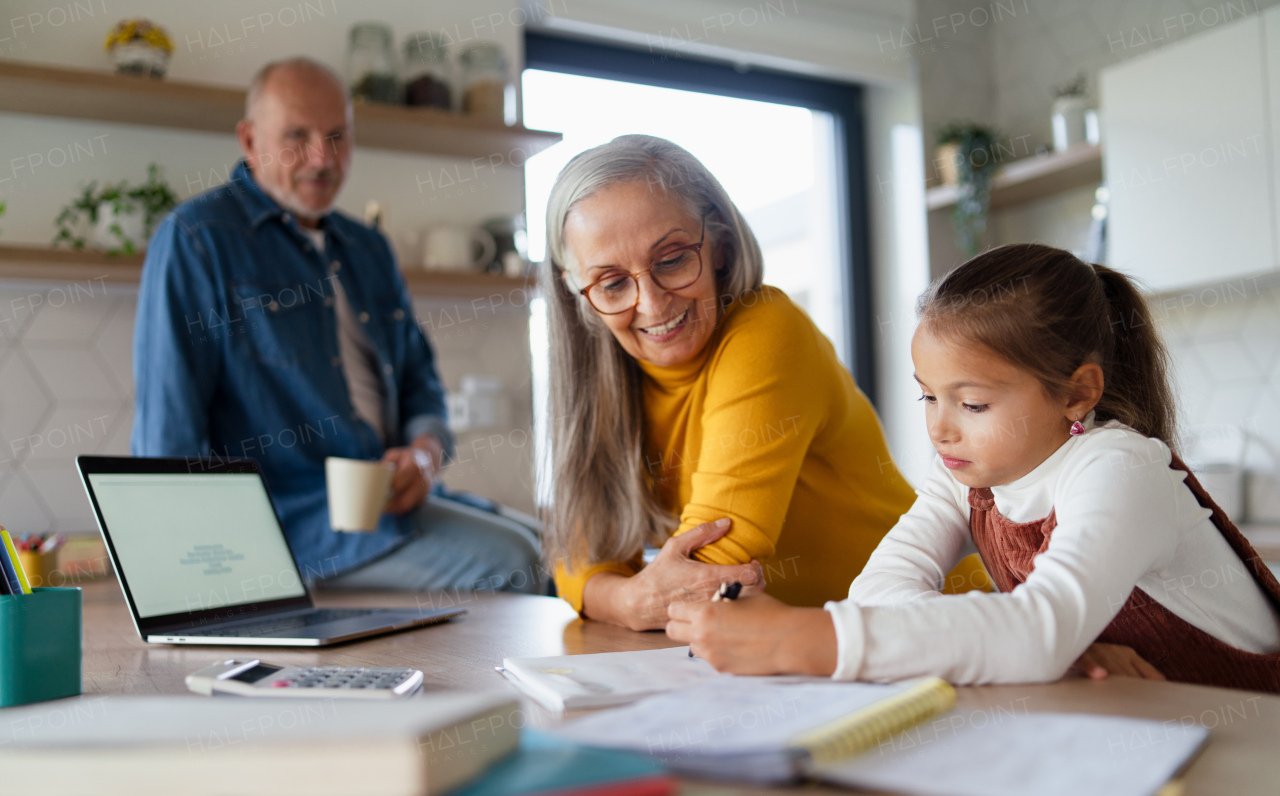 A small girl with senior grandparents doing maths homework at home.