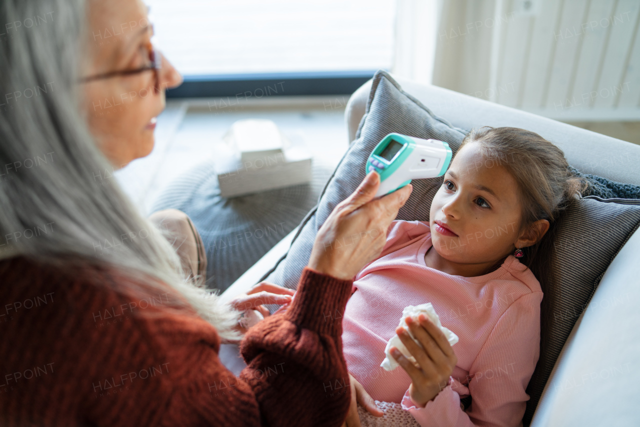 A grandmother taking care of her ill grandchild lying on sofa