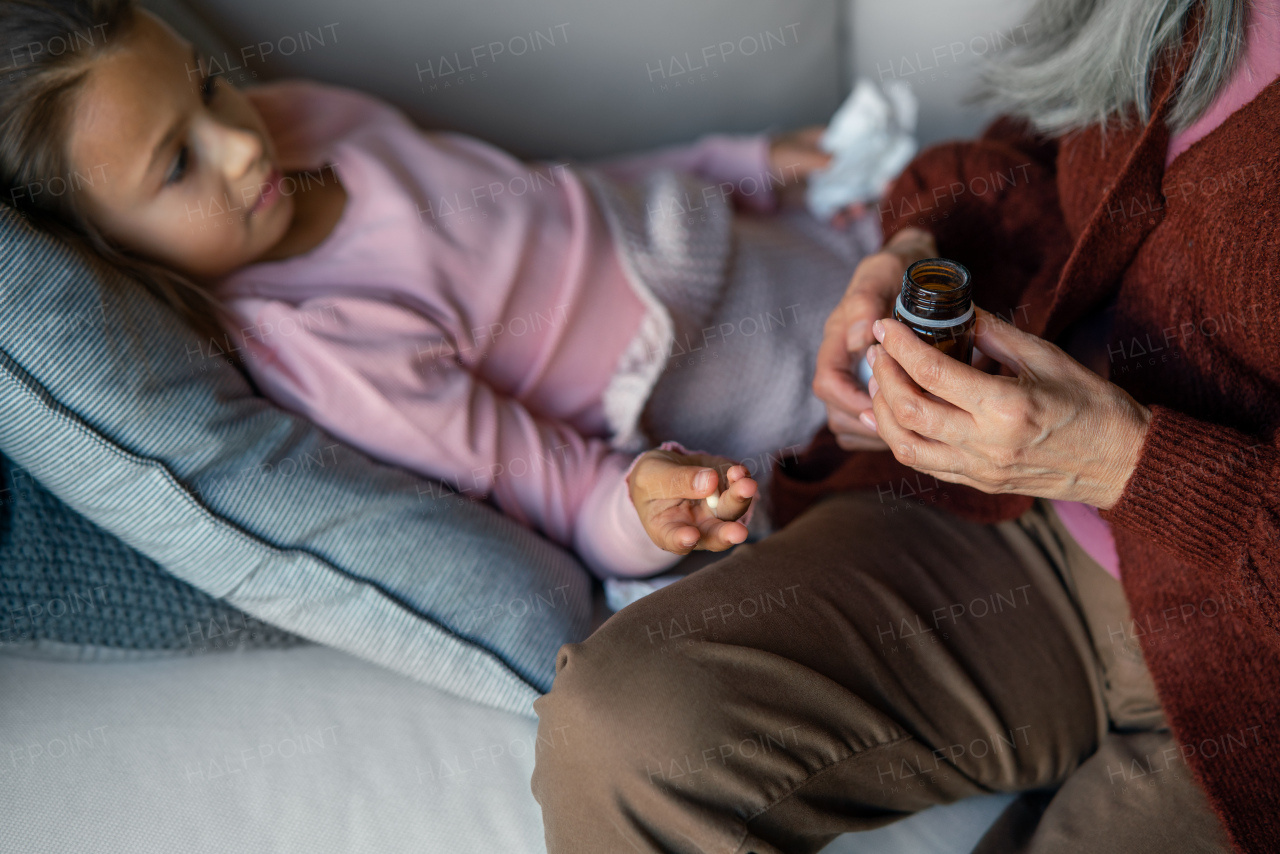 A grandmother taking care of her ill grandchild lying on sofa