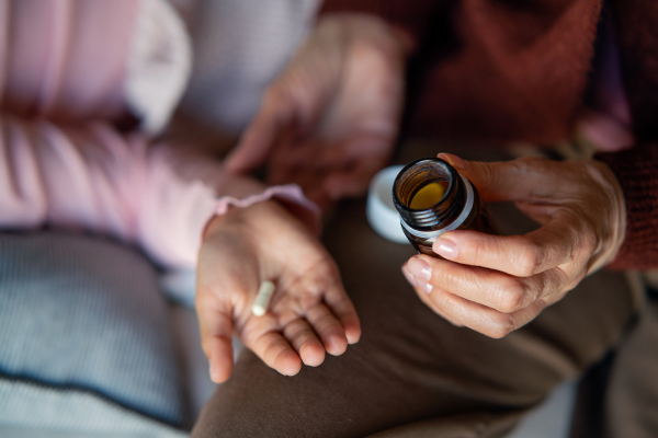 A close-up of grnadmother's hand giving medicine to her grandchild.