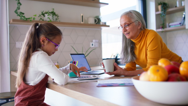 A small girl with grandmother doing homework at home.