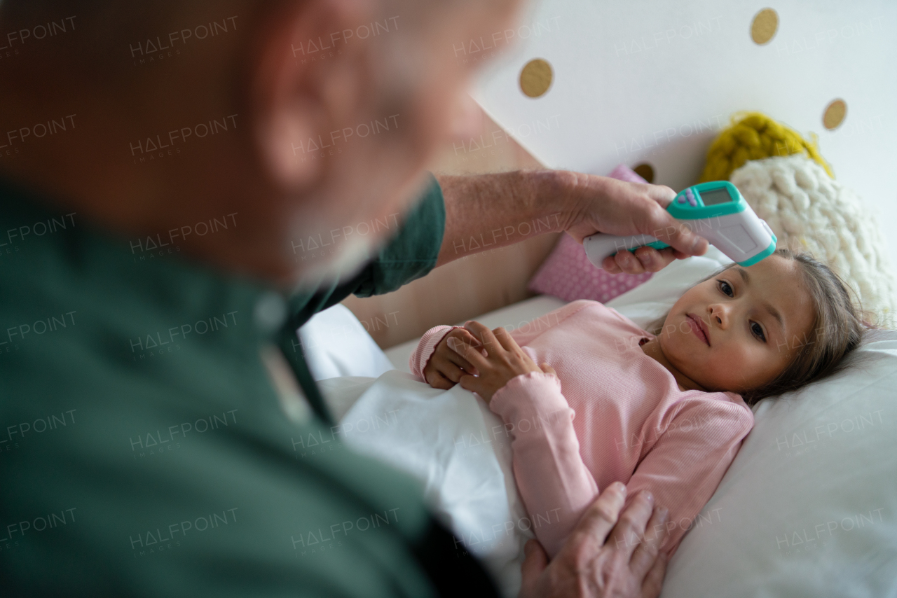 A grandfather taking care of his ill granddaughter lying in bed.