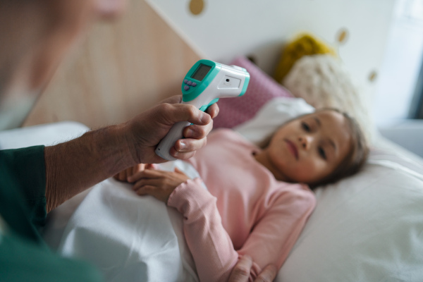 A grandfather taking care of his ill granddaughter lying in bed.