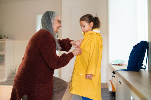 A grandmother helping granddaughter to get ready to leave home for school.