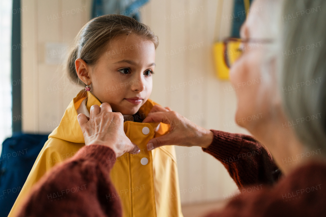 A grandmother helping granddaughter to get ready to leave home for school.