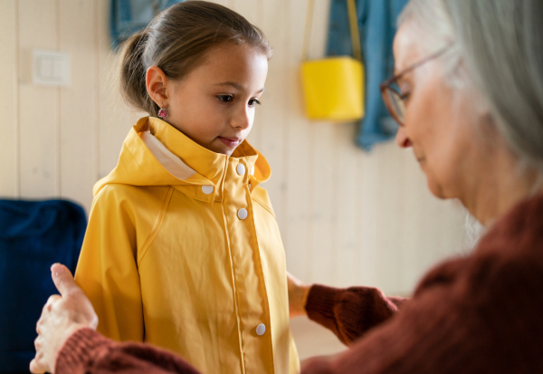 A grandmother helping granddaughter to get ready to leave home for school.