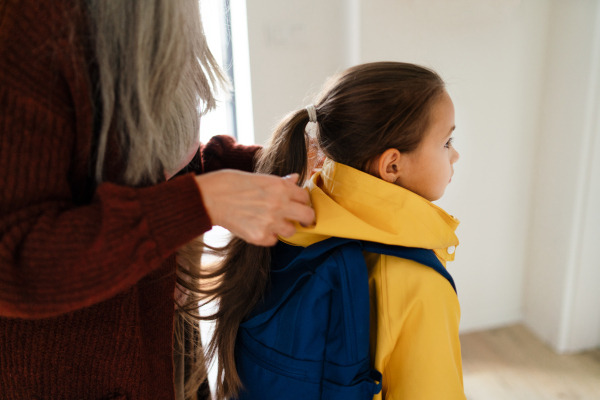 A grandmother helping granddaughter to get ready to leave home for school.