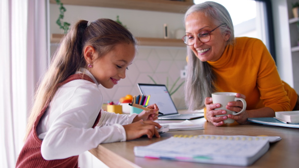 A small girl with grandmother doing homework at home.