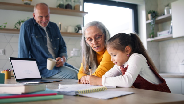 A small girl with senior grandparents doing maths homework at home.