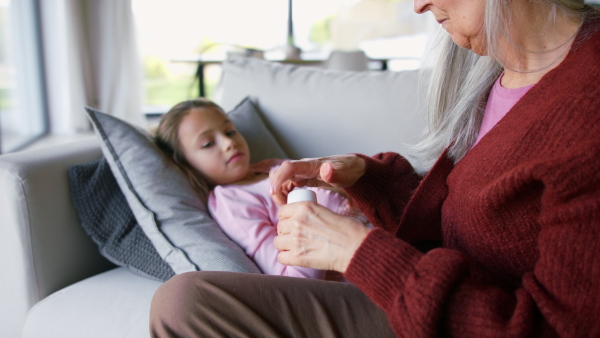 A grandmother taking care of her ill grandchild lying on sofa