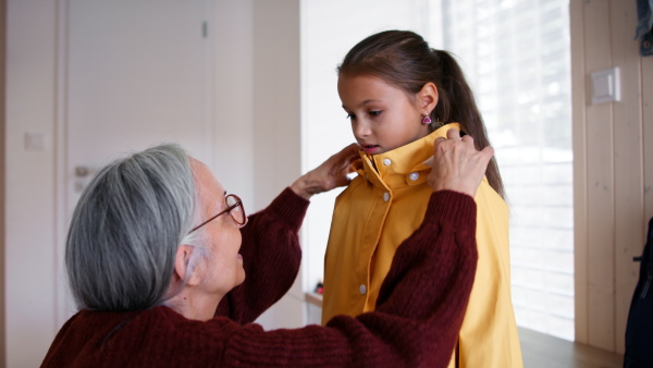 A grandmother helping granddaughter to get ready to leave home for school.