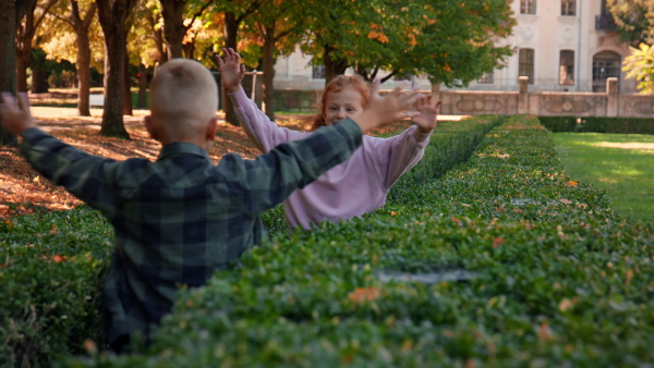 A happy little girl running to hug her brother outoodrs in park in autumn