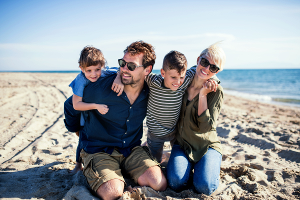 Portrait of young family with two small children sitting outdoors on beach.