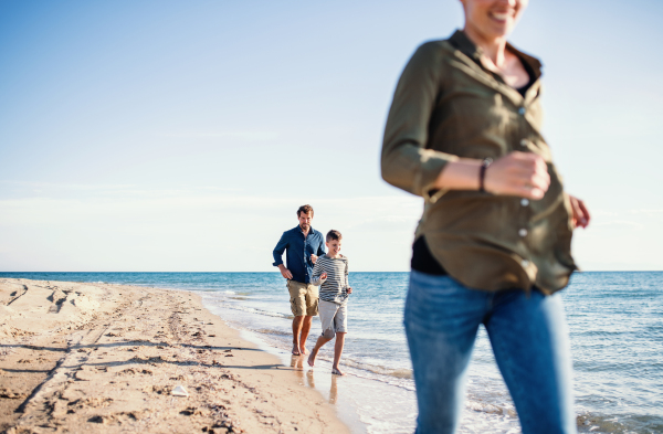 Young family with small son running outdoors on beach, a midsection.