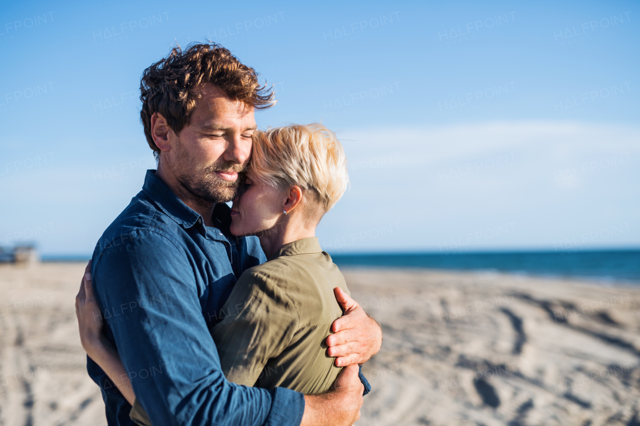 A young couple standing outdoors on beach, hugging. Copy space.