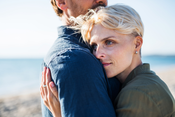 A midsection of young couple standing outdoors on beach, hugging. Copy space.